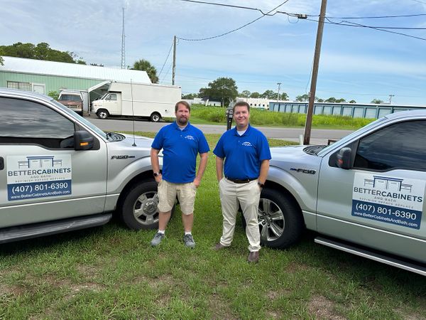 Founders Nick and Lee standing between two Better Cabinets & Bath work trucks
