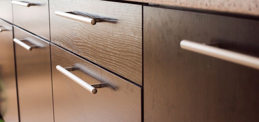 Close-up of new wood-grain kitchen cabinet doors with brushed metal bar pulls