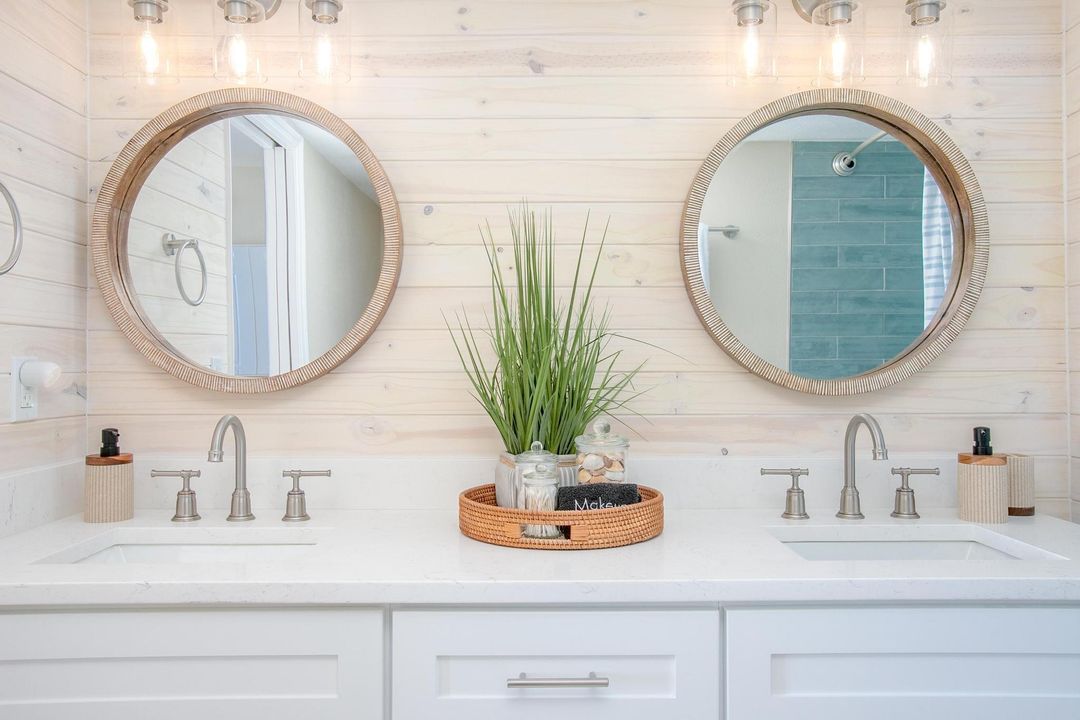 Refaced white double vanity with round wood-framed mirrors and a whitewashed plank wall