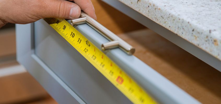 Tape measure on a cabinet drawer while fitting new hardware