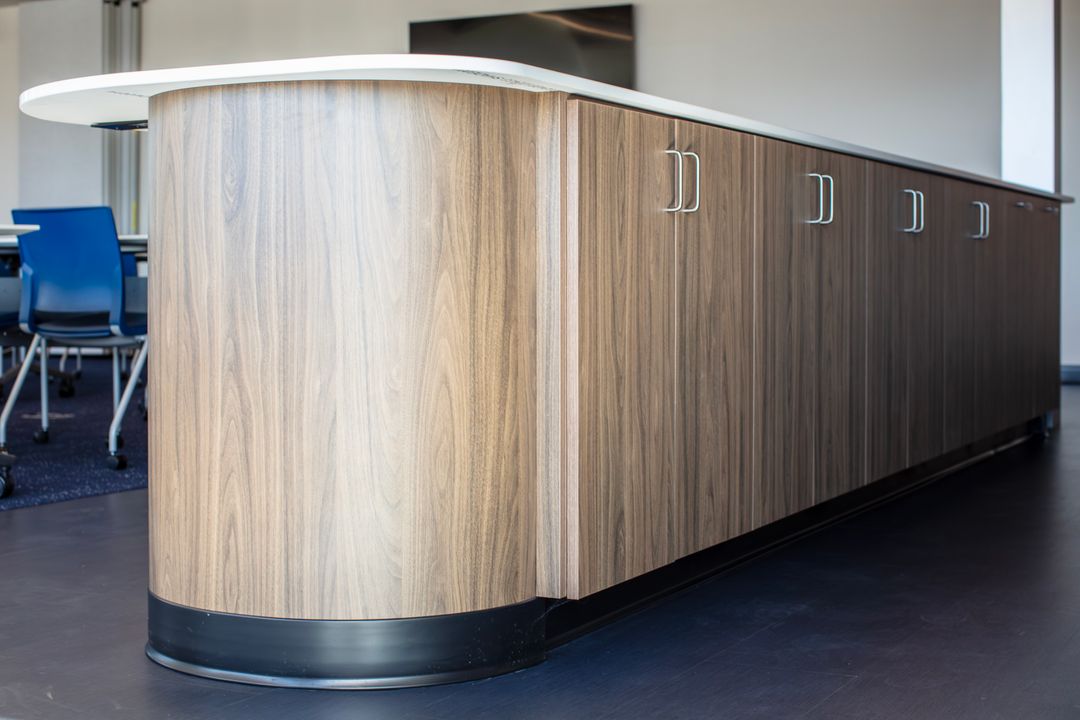 Woodgrain TFL commercial island in Omaha with curved end panel, long cabinet run, silver pulls, and extended light countertop. Commercial Island Cabinet, Omaha