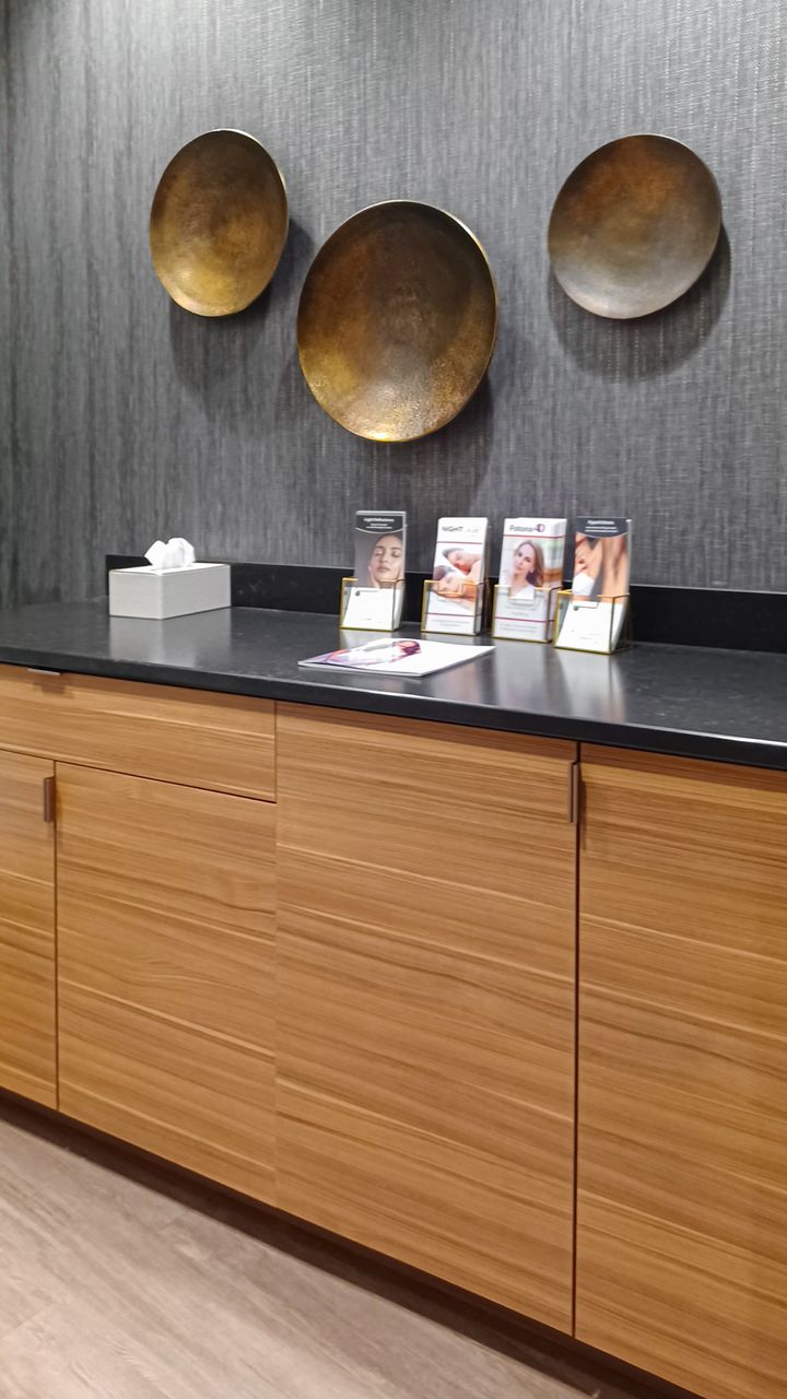 Horizontal woodgrain TFL commercial cabinetry in Omaha with black countertop, backsplash, and decorative wall accents above the counter. Commercial Cabinetry, Omaha
