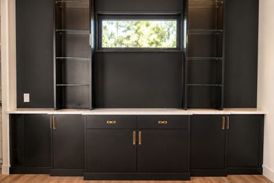 Home office wall with black cabinets and glass shelves