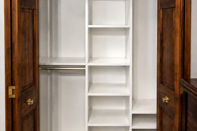 Reach-in closet with white shelves and wood double doors