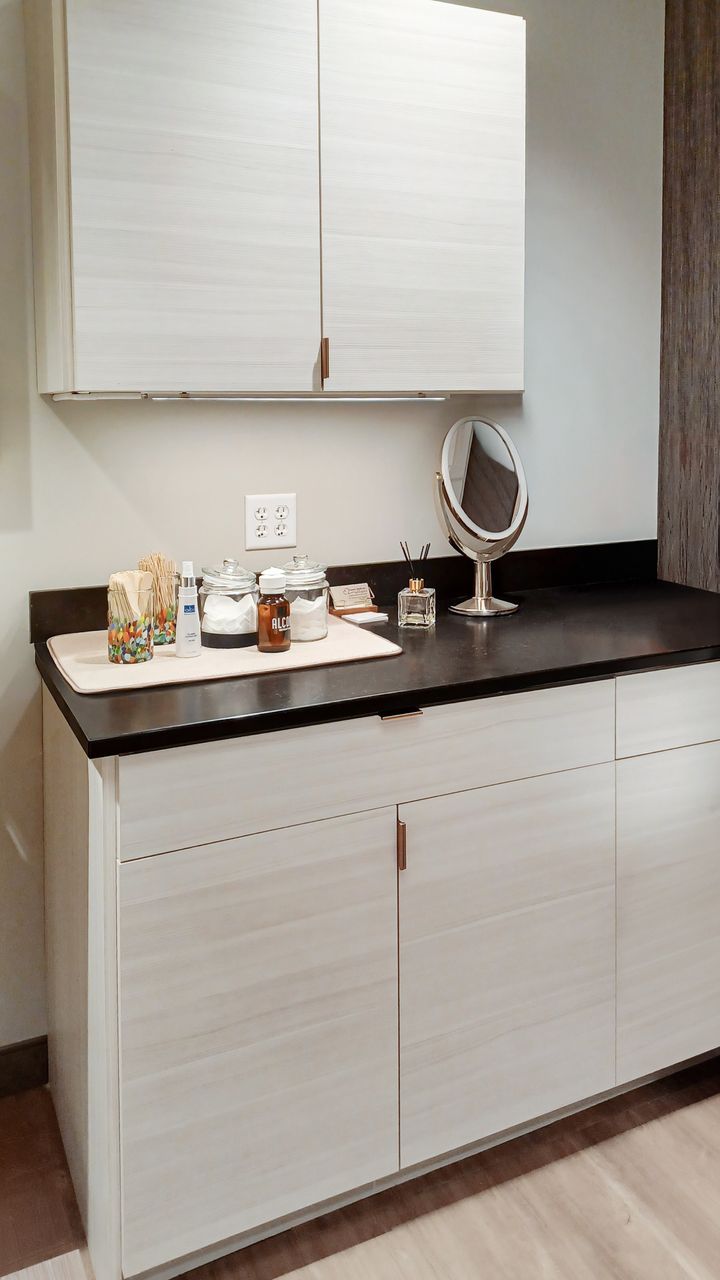 Light TFL commercial cabinetry in Omaha with black countertop, upper and lower cabinets, and small decorative items arranged on the counter. Commercial Cabinetry, Omaha