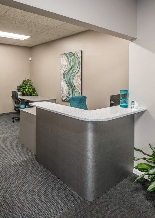 Curved reception desk in Omaha with metallic paneling, light countertop, and workspace seating in a commercial office setting. Commercial Reception Desk, Omaha