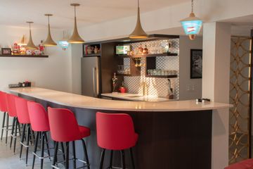 Custom Home Bar with Curved Counter and Red Bar Stools in Omaha