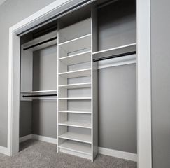 Reach-in closet in Omaha with a white TFL shelf tower, adjustable shoe shelves, and double-hang sections framed by painted trim. Reach-In Closet, Omaha