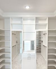 Large Omaha walk-in closet with white TFL shelving, drawers, and a vanity mirror framed by built-in storage. Custom Walk-In Closet, Omaha