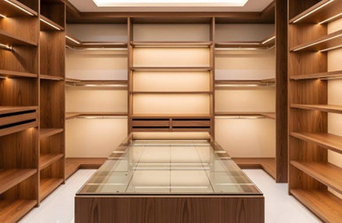 Walk-in closet with walnut shelving, warm LED lighting, and a glass-top center island