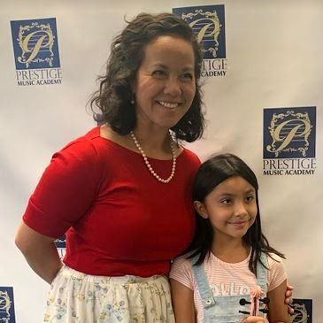Proud instructor Anna assisting her pink violin student on recital day