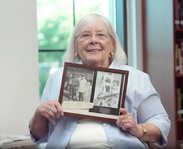 Longtime donor holding a framed photo in her home