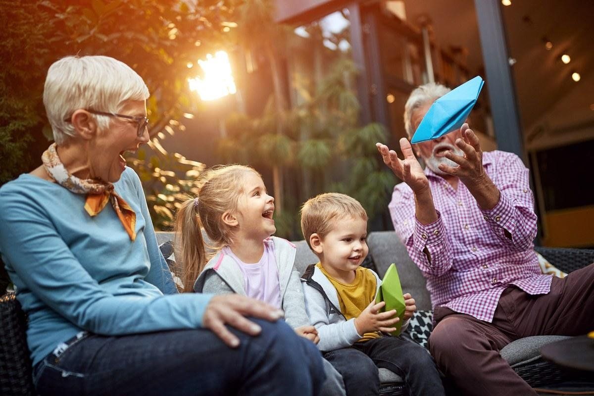 Grandparents laughing with their young grandchildren on a porch at sunset