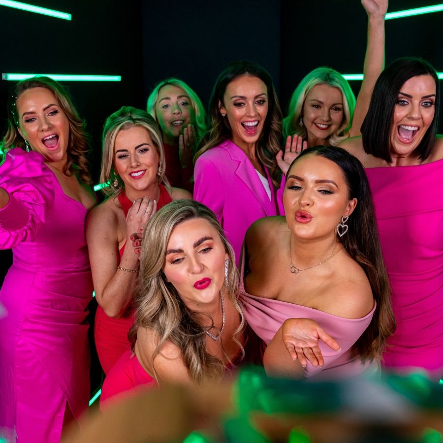 Group of women in pink outfits celebrating in a Vogue Photo Booth