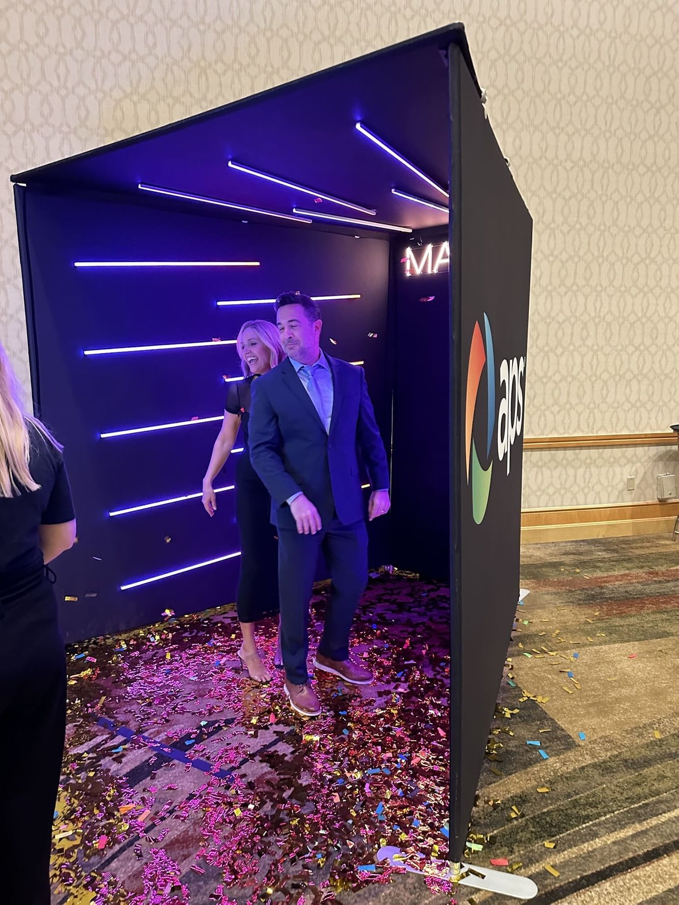 Branded booth with APS logo, Mame customized led light havning in the background. 