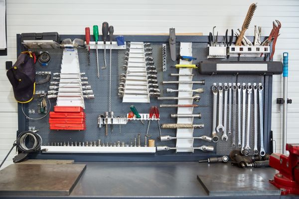 Garage wall panel holding wrenches, screwdrivers, and hand tools over a workbench